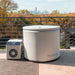 Lidded Revive Inflatable Pod Plunge Cold Plunge Pool and chiller on a rooftop deck framed by autumn trees