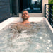 Man relaxing neck-deep in thick ice sheets inside the Revive Acrylic Plunge Tub on a balcony