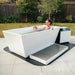 Woman smiling while seated in the Revive Acrylic Plunge Tub with step, mat and chiller in a backyard