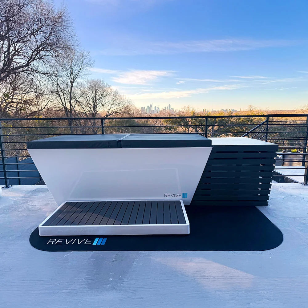 Revive Plunge Chiller Protective Cover set beside a closed acrylic plunge tub on a rooftop deck at sunrise