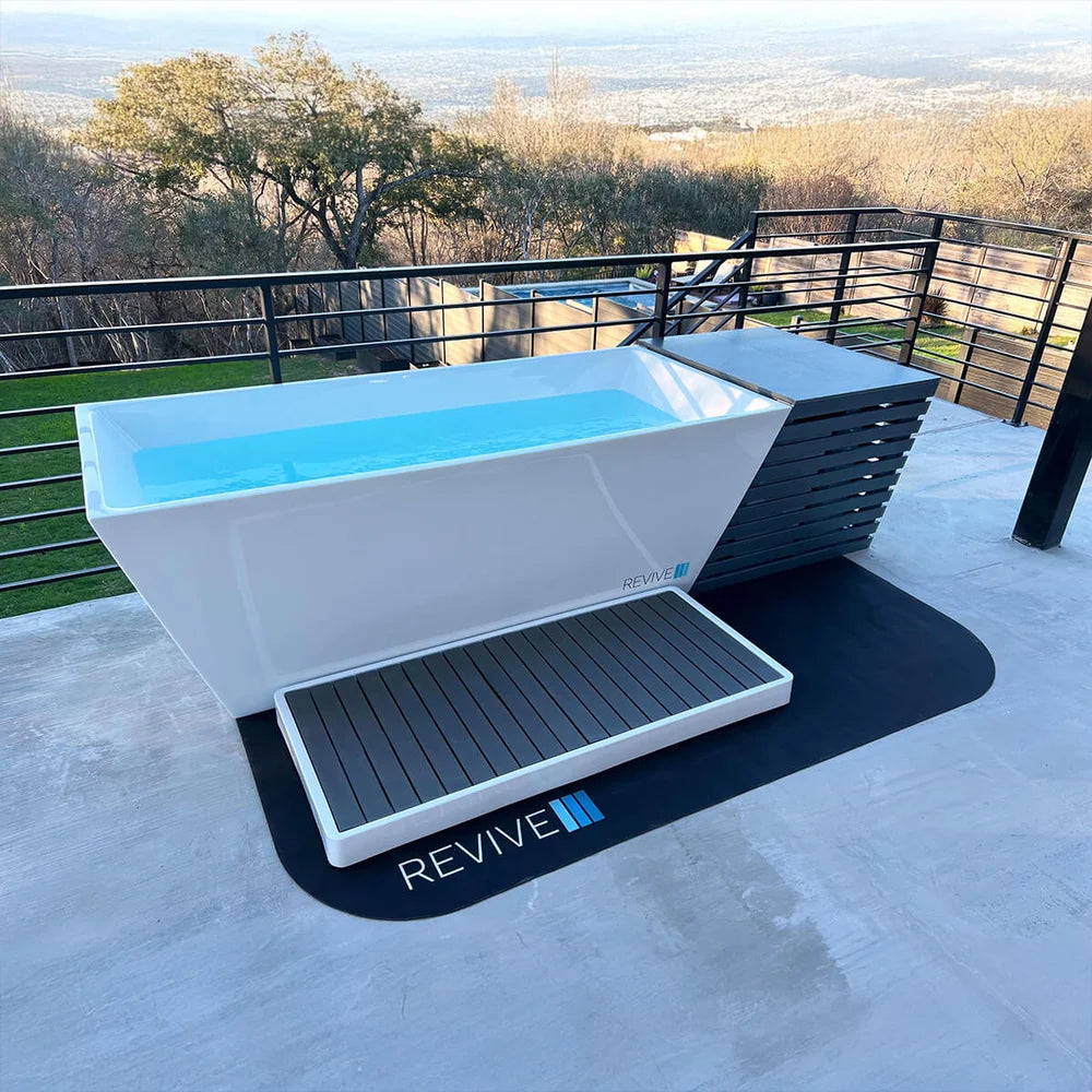 Hillside patio setup with the Revive Chiller Cover behind a water-filled plunge tub and dark slatted step