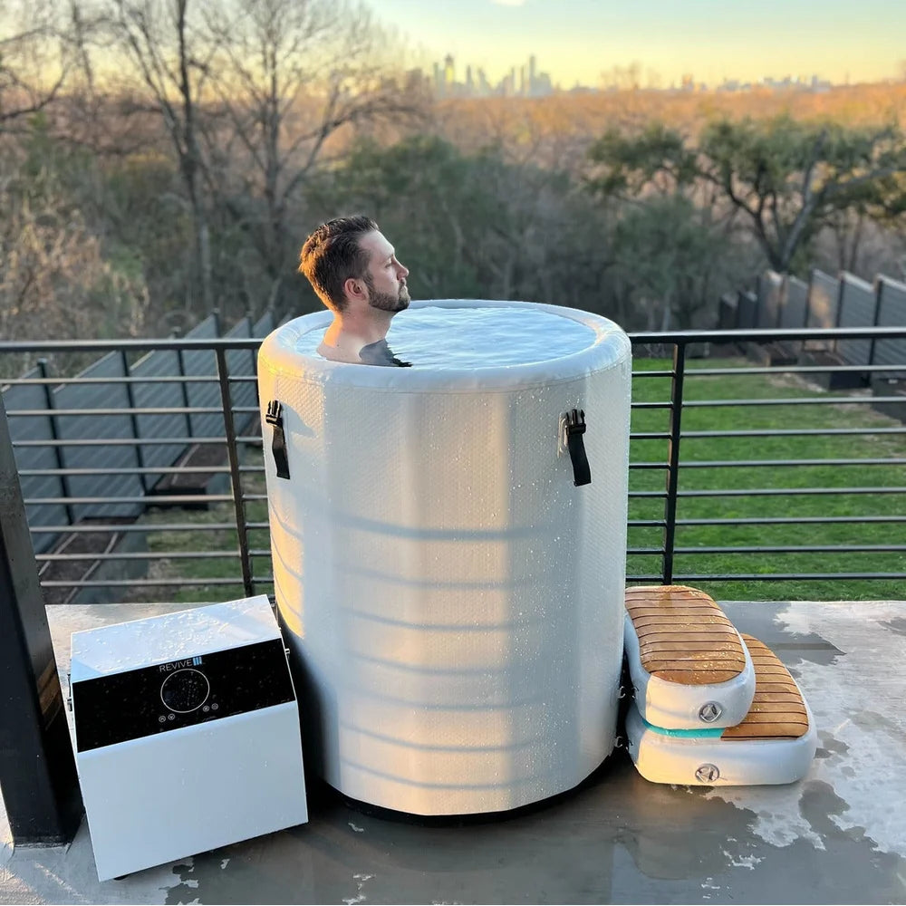 Rooftop sunset soak showing the chiller and step beside the Revive Plunge Inflatable Barrel Plunge Cold Plunge Tub