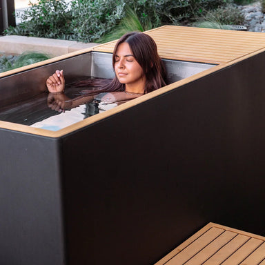 Woman relaxing in the water of the Revive Plunge Luxury Plunge Cold Plunge Tub on an outdoor patio