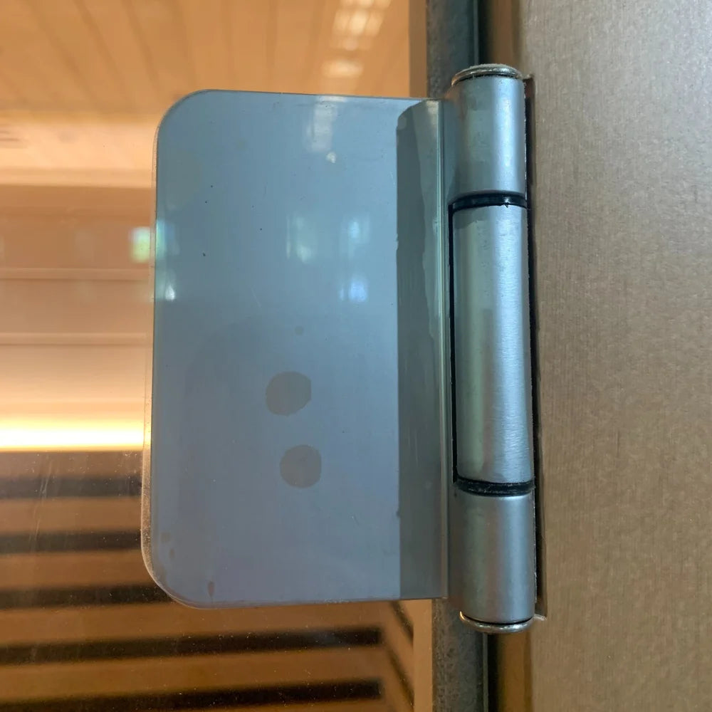 Polished steel hinge holding the tempered glass door on the Blisspod Bergen Sauna Pod cabinet frame