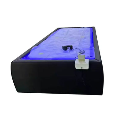 Black Tsb360 Dry Float Bed at an angle with blue-lit membrane, headphones and wired handheld controller on the side