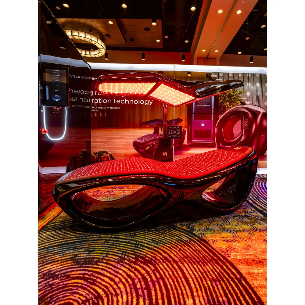 Side profile view of the Tsb360 Longevity Bed Therapy & Recovery Bed in a showroom booth with glowing red canopy