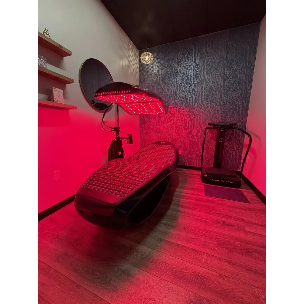 Wide spa room view of the Tsb360 Longevity Bed PEMF Therapy Bed beside a vibration plate on wood flooring