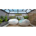 Pair of Dreampod Home Float Plus Float Tank pods, one open one closed, in a glass-roofed garden room