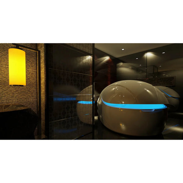 Two pods in a dark spa lounge with a bright blue door light band, the Dreampod Vmax Isolation Pod mirrored in glass