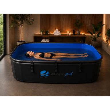Woman floating on her back in the blue-lined water of the Dreampod Home Float FLEX Float Pod in a home spa room