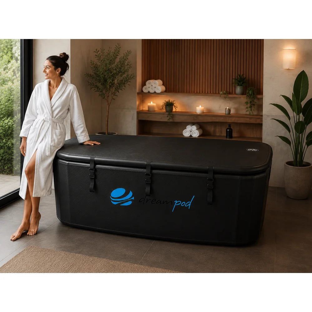 Woman in a white robe resting a hand on the closed lid of the Dreampod Home Float FLEX in a spa-styled room