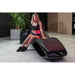 Woman seated on the glowing LED lounger of the Vacu Activ Red Couch Oxy Therapy Device beside its oxygen unit